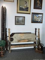 Front view of antique wooden bed frame headboard and footboard with chipped paint and rope support rails visible.