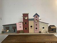 Full frontal view of birdhouse village wall hanging displaying six birdhouses mounted on a single base, featuring attached bird figurines.