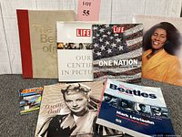 Photo showing all items in the lot: hardcover books, magazines, biography books, music chronicle, and a vinyl record album, along with a small booklet titled 'New York State'.