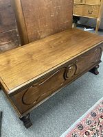 Side/Top view of the cedar chest showing walnut stain finish, smooth wood surface, and carved legs.