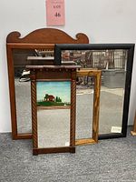 Set of four framed mirrors of various sizes and styles displayed leaning against a wall.