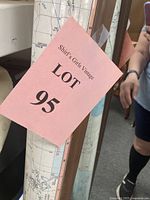 Photo of the laminated map rolled and partially visible with a pink lot number 95 tag attached. The image shows part of the map's geographic details and the wood rail on the top edge.