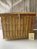 Front view of large rectangular wicker hamper basket showing woven rattan wicker with hinged lid and clasp.