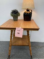 Full view of the wooden side table with the ceramic lamp and faux lavender plant on top, showing table surface and items.