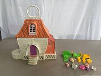 Closed Charmkins dollhouse playset with small assorted accessories placed around it
