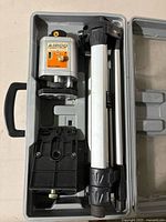 Open gray plastic carrying case displaying Airco ALL500 laser level, small tripod, and mounting bracket inside.