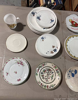 Photo showing an assortment of white and floral patterned plates along with a white mug decorated with a sunflower pattern.