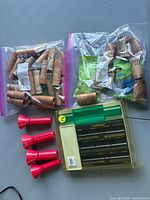 View of four red plastic coin counters/funnels, Coin Masters counting device, and two bags of assorted coin rolls.