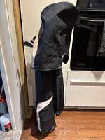 Full side view of the black and beige Cadie Bear golf bag standing upright indoors on wooden floor.