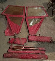 Two metal-framed doors with plastic windows and red canvas laid on floor with additional rolled canvas pieces and poles around them.