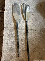 Full view of both kayak paddle blades and shaft showing markings, condition, and lure recovery hook feature.