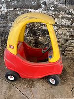 Side view of red and yellow Little Tikes Cozy Coupe ride-on toy car showing the profile including wheels and body shape.