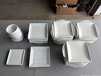 Overview of all stacked white porcelain plates and bowls on table showing all sizes and counts