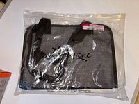 Thirty One Get Creative Caddy bag packed in a clear sealed plastic bag showing the charcoal crosshatch material and black handles.