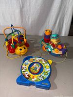 Three toddler pull toys displayed: Ladybug wire bead maze, Winnie the Pooh pull toy, and See'n Say farm animal spinner.