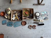 Full lot overview showing the mixed collection of bowls, tins, plaques, buttons, cigars box, clock, and other trinkets