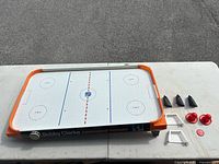 Top-down view of air hockey table with all accessories laid out on white table.