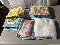 Folded assorted vintage cotton sheets, pillow covers, and fabric pieces arranged on table.