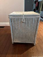 Front view of rectangular wicker storage container with woven lid and loop latch.