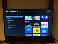 Front view of Sharp Roku TV powered on showing home screen interface