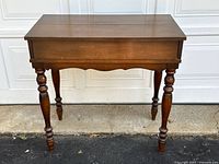 Front view of the closed antique walnut spinet desk showing rectangular top and turned legs.