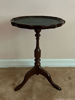 Round pedestal drink table with green leather top and wood scalloped rim, full view from front.