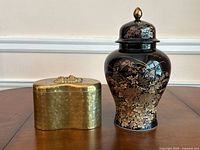 Photo showing both the ceramic urn and the brass lidded box side by side on a wooden surface.