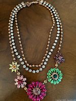 Full view of the necklace showing double strands of copper tone beads and clear rhinestones with five colorful rhinestone floral clusters.