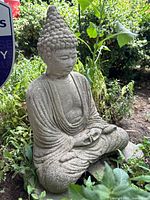 Side angle showing Buddha sculpture seated in garden with surrounding greenery.