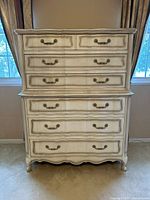 Front view of French Provincial-style 7-drawer dresser with cream finish and metal handles in natural indoor lighting.