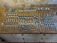 Full layout of flatware spread on countertop showing forks, knives, spoons and serving pieces