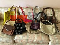 View of all 11 bags laid out on patterned couch showing variety of colors, sizes, and styles