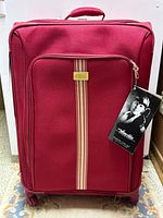 Front view of red Amelia Earhart spinner luggage with stripes and badge.
