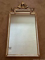 Full front view of the mirror showing rectangular shape and decorative crest