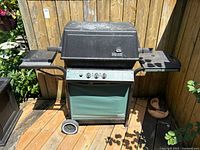 Front view of black Broil-Mate propane gas barbecue grill with folded sides, attached wheels, and covered panel below.