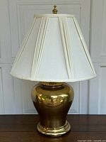 Full front view of the vintage brass table lamp showing the polished brass base and white pleated fabric shade.