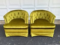 Two green velvet barrel lounge chairs side by side, front view