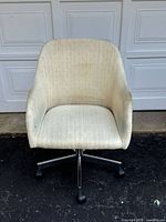 Front view showing curved backrest and seat with off-white fabric upholstery, some visible stains.