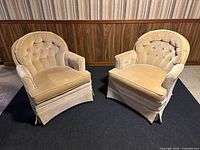 Pair of beige vintage velvet tub chairs with rounded tufted backs, skirted bases, showing some wear and staining