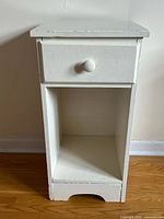 Front view of vintage white painted wood nightstand showing drawer and open storage space below