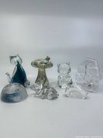 Full lot arranged showing all six art glass paperweights including cat, mushroom, bear, dog, abstract, and beetle designs.
