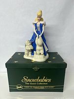 Front view of the porcelain figurine on its original box showing Barbie with two snowbaby figures.