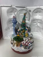 Front view of Disney Store double snow globe with classic Disney characters, winter village base, and castle tower.