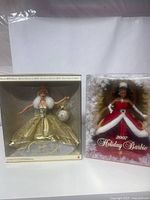 Photo showing both boxed dolls standing next to each other showcasing front of packaging and dolls inside.