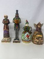 Front view of all four Jim Shore Heartwood Creek Christmas themed figurines: woman caroler, man caroler, snowman, and angel.