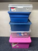 Stack of five plastic storage bins of various sizes and colors including clear, blue, and pink.