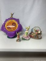 Lot showing all four items together: Tinker Bell CD player, small Jim Shore figurine, larger Tinker Bell figurine, and music snow globe.