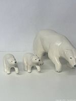 Front angle showing large adult ceramic polar bear and two smaller baby bears, white with black details.