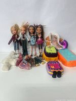 Four vintage Bratz dolls with cut hair standing upright alongside various doll accessories including shoes and fabric doll furniture pieces.