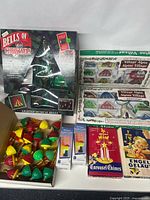 Overview of all Christmas decor items including boxed Mr. Christmas Bells of Christmas, Alpine Village sets, Holiday Night Lights, Carousel Chimes and string lights box.